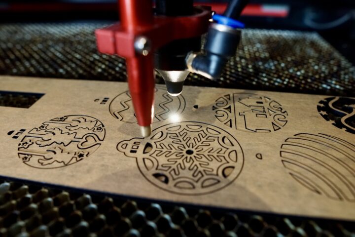 A laser cutter firing into acrylic to cut out Christmas ornaments.